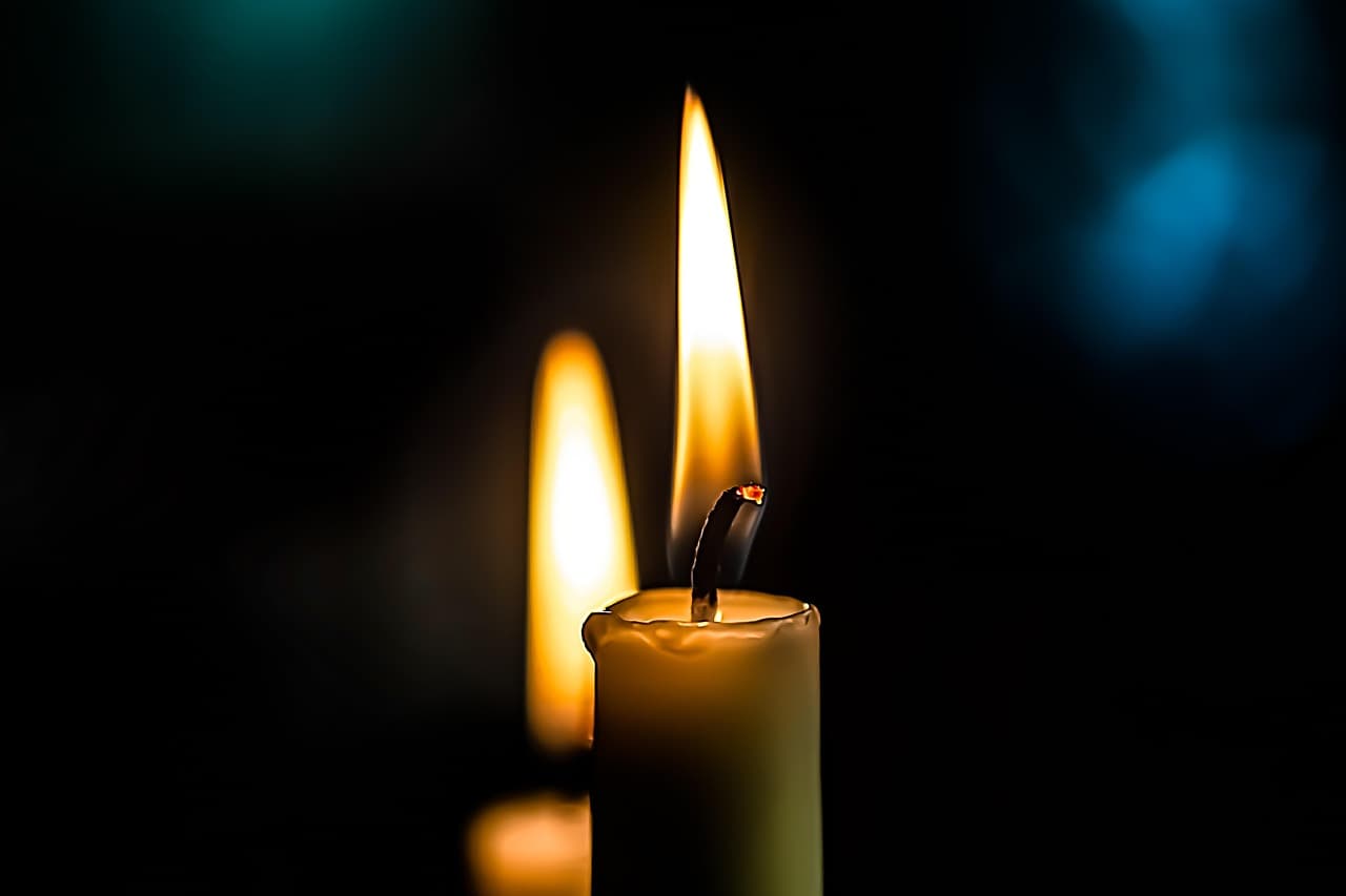 Flackernde Kerzenflamme wirft wechselnde Lichter auf Hautkonturen, warme Schatten