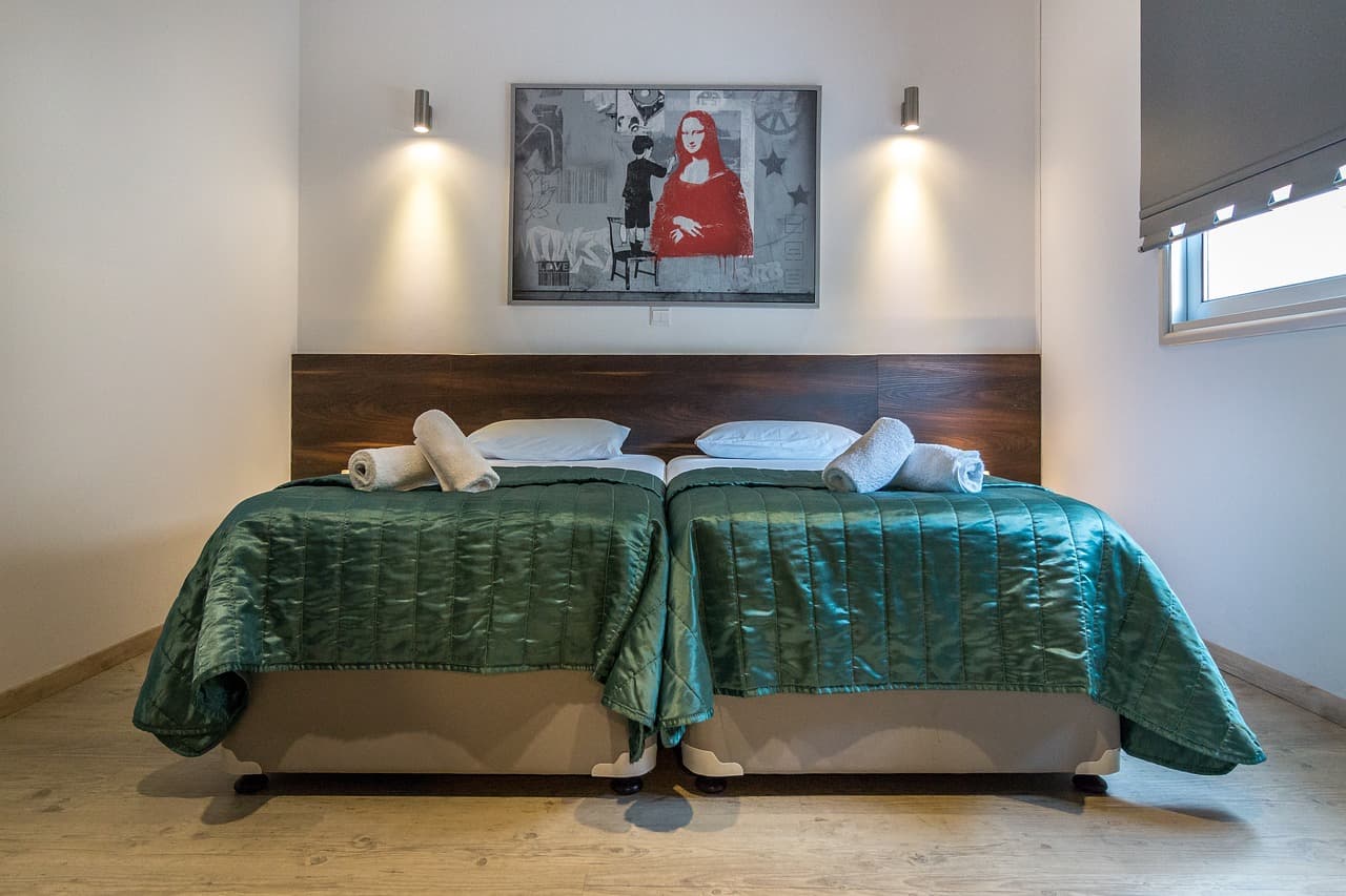 Weißes Hotelbett vor Fenster mit Meerblick, sommerliches Licht