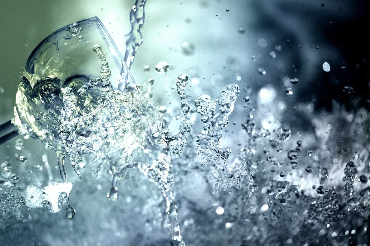Wasser spritzt in Nahaufnahme aus einem gekippten Trinkglas