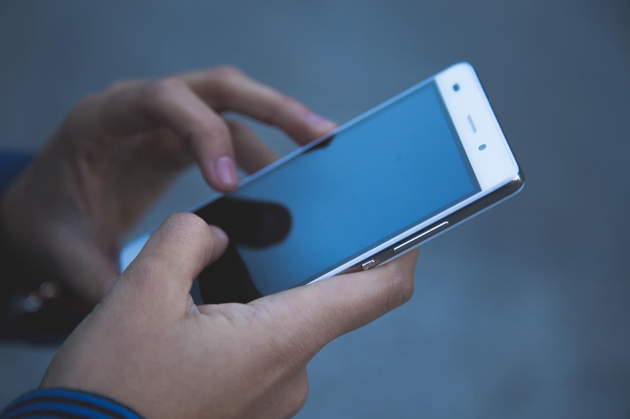 Hände halten ein Smartphone mit dunklem Display