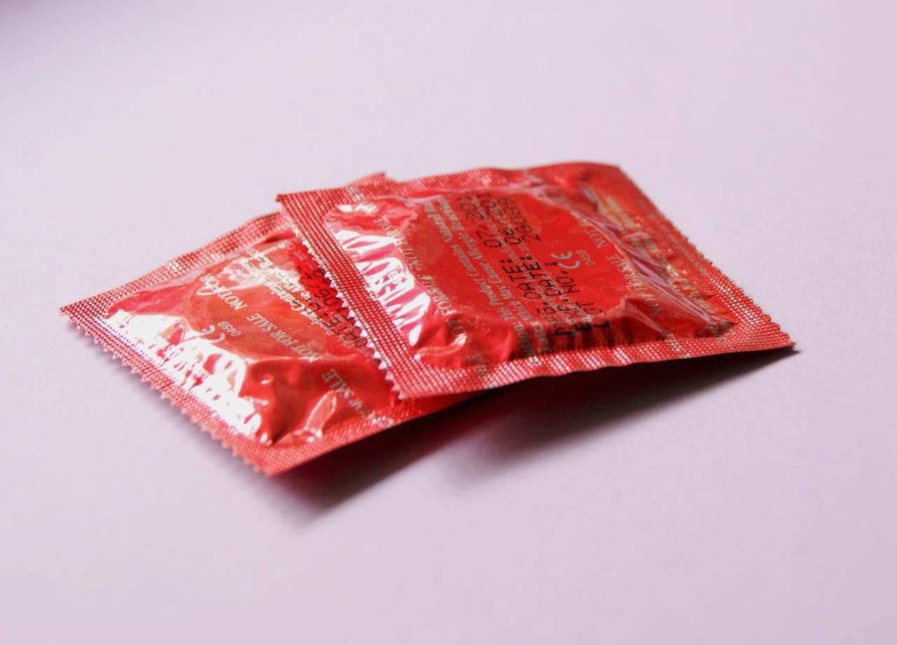 Zwei verpackte Kondome in roter Folie auf hellem Untergrund