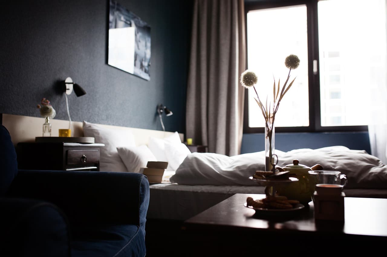 Schwach beleuchtetes Hotelzimmer mit einer halb geöffneten Tür, draußen die Lichter einer fremden Stadt